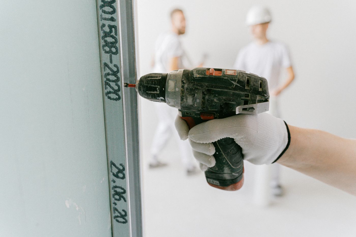 Drywall professional fastening sheetrock to framing with a drill