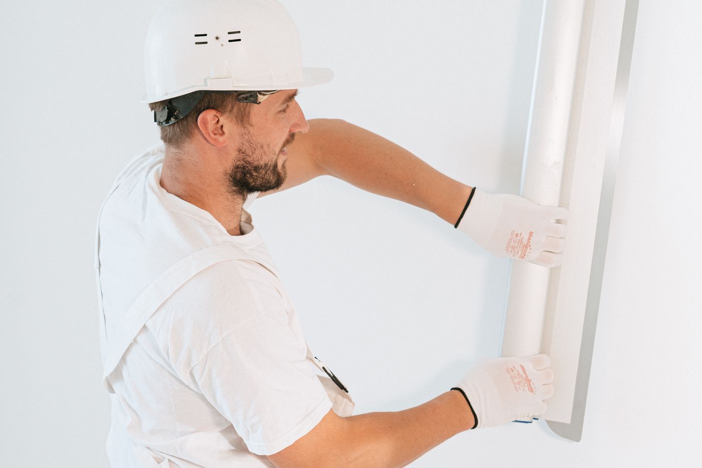 Drywall professional leveling a wall surface with a straightedge