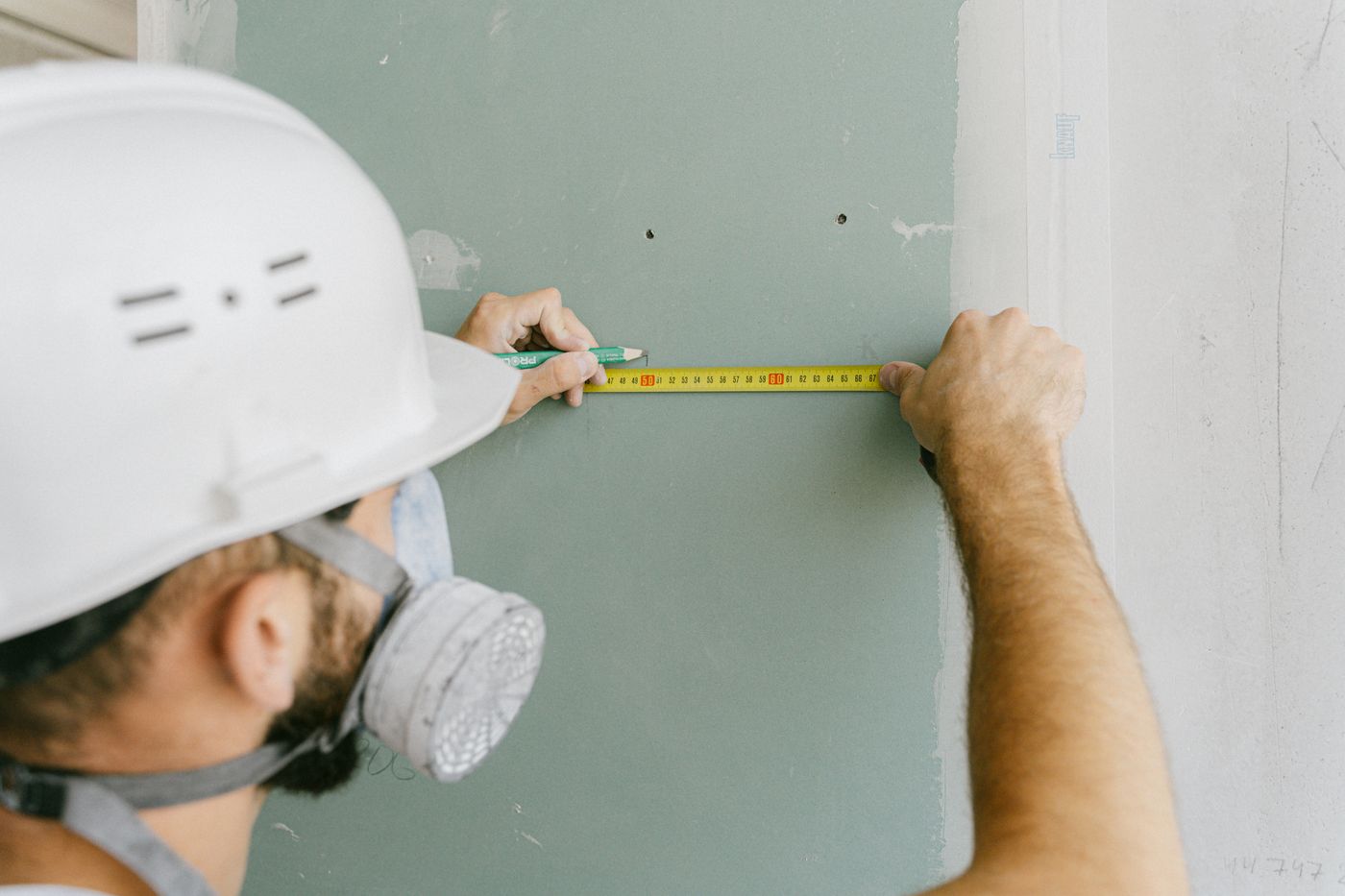 Drywall professional measuring and marking a sheetrock panel