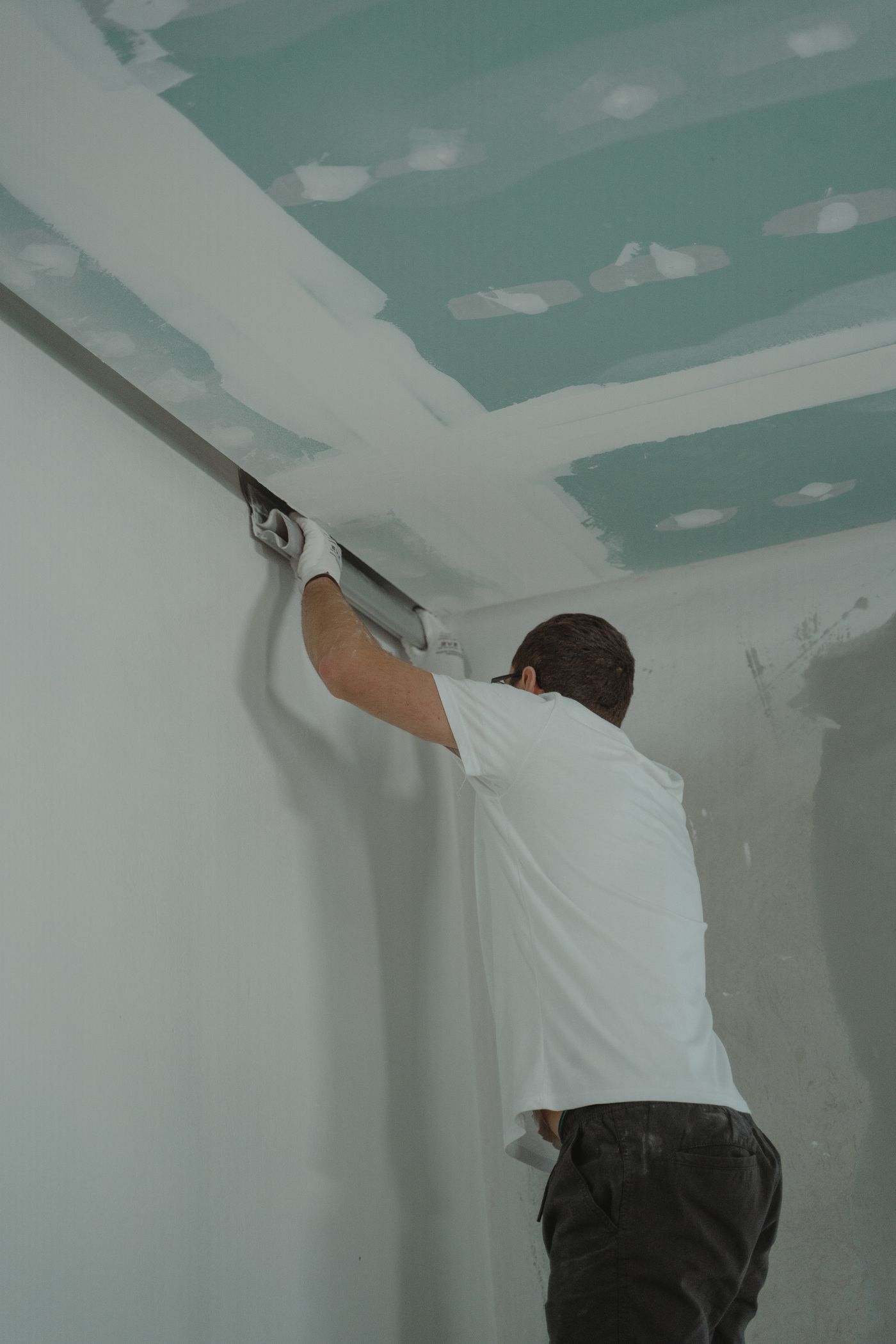 Drywall finisher running a taped ceiling joint